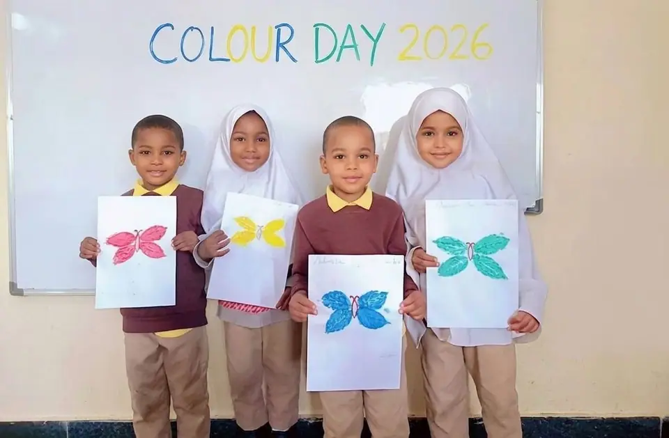 Four pupils holding up butterfly paintings in front of a whiteboard that reads Colour Day 2026