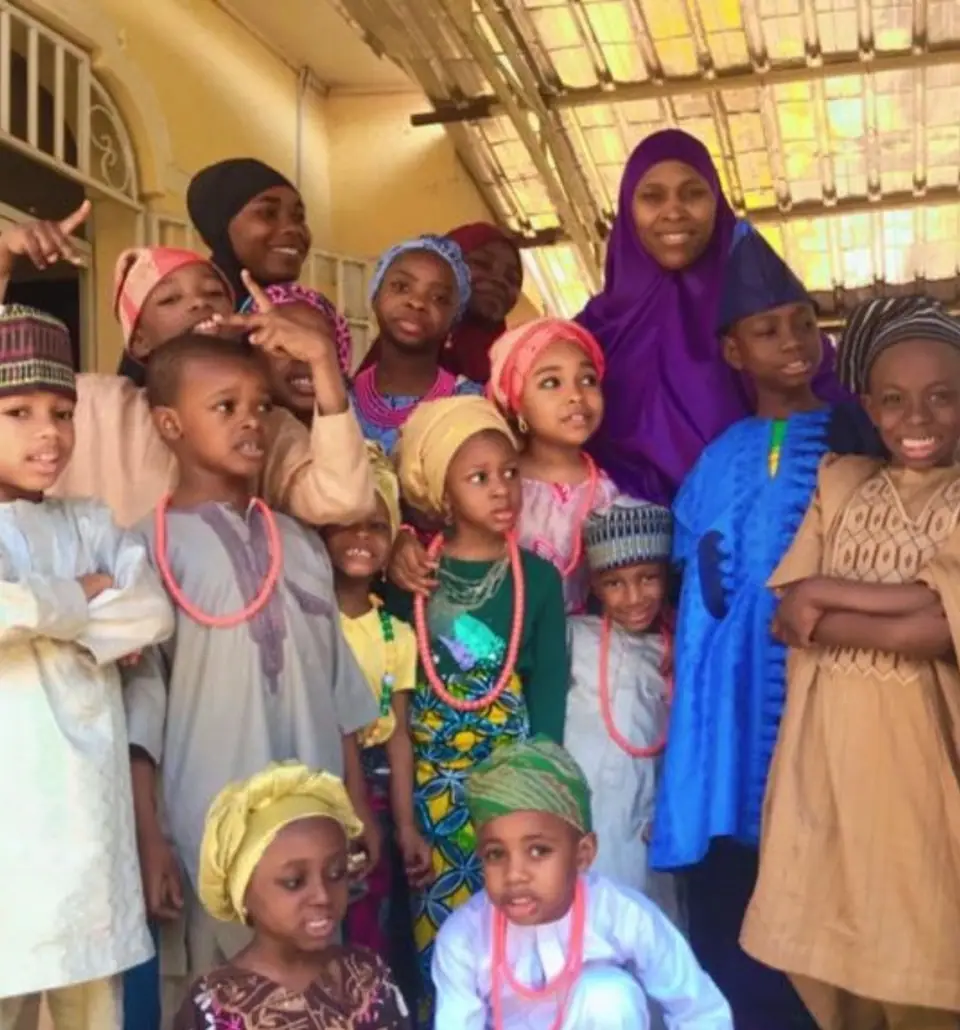A large group of pupils in traditional dress with two teachers in the school corridor