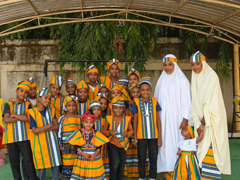 Pupils in striped cultural day outfits with two teachers in the school playground